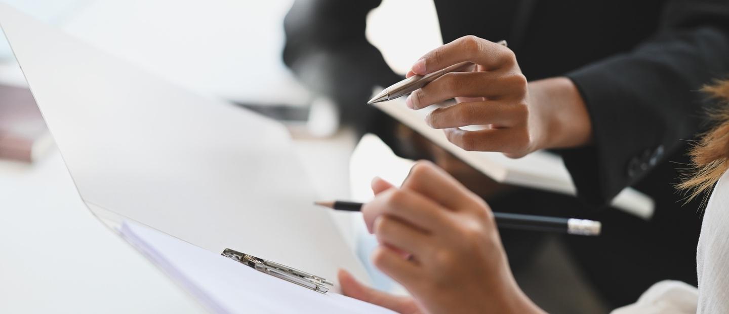 Closeup of hands holding pens and paper.